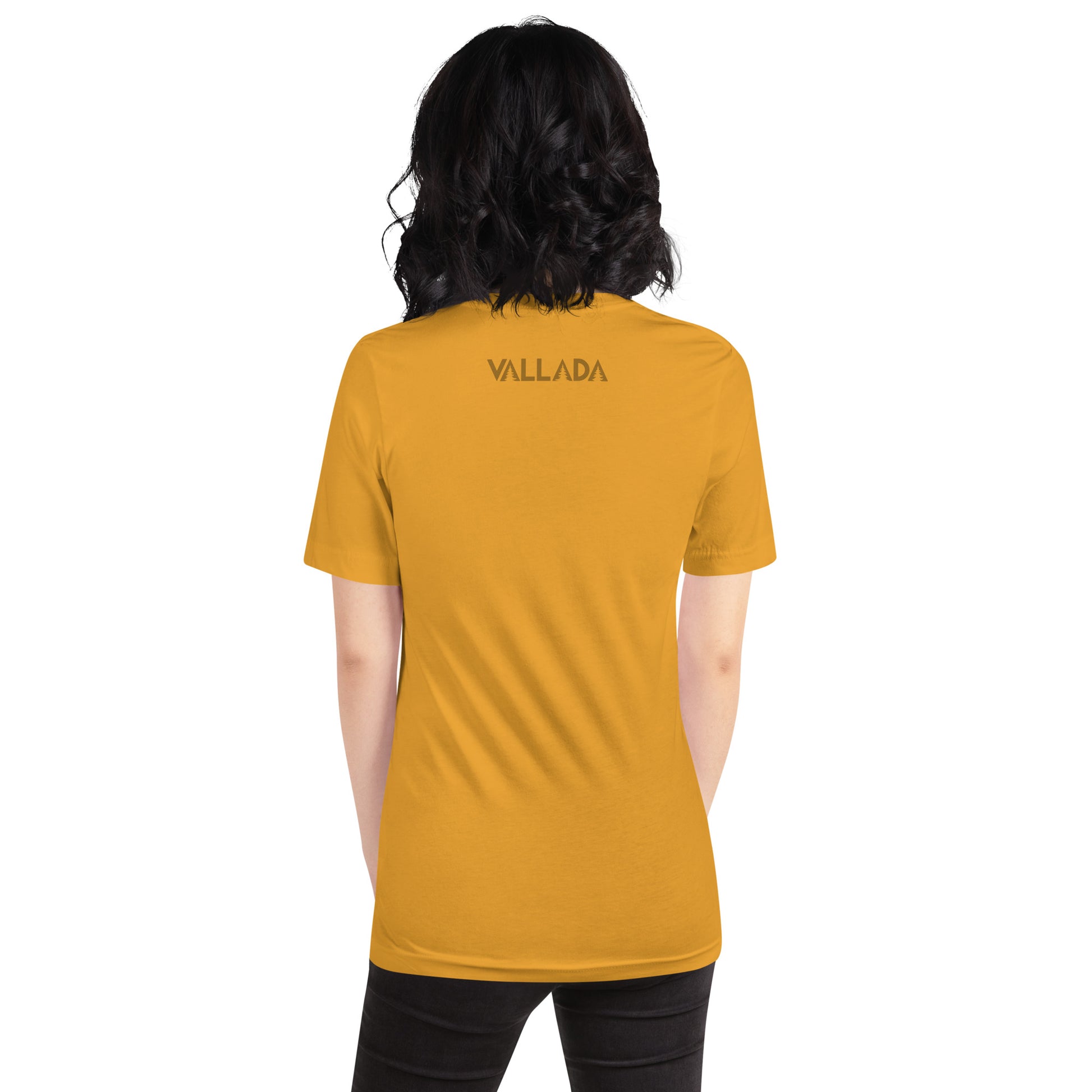 Diese Wanderfreundin trägt ein senffarbenes Damen T-Shirt aus der Säntis-Collection von Vallada. Sie steht mit dem Rücken zur Kamera, so dass wir das Vallada-Logo sehen.