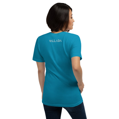 Sie steht mit dem Rücken zu uns, damit wir den Schriftzug der Marke Vallada auf ihrem T-Shirt in der Farbe Türkis sehen können.